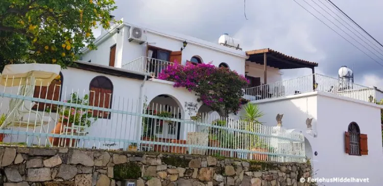 Pen villa i hvit mur med veranda med gjerde, pergola og en bogainvilleabusk i Ilgaz kypros