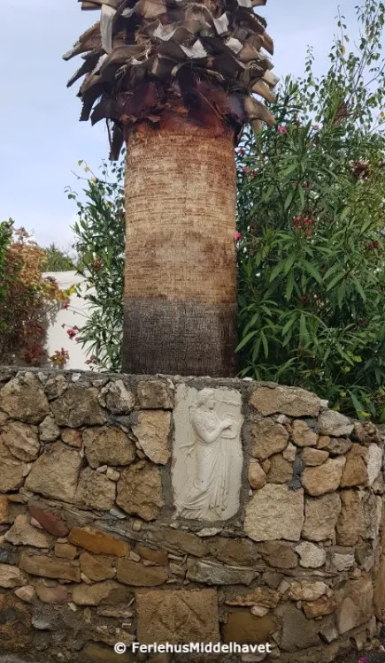 Stor flis med en harpespillende engel i en steinmur med en palme bak i Ilgaz village Nord Kypros
